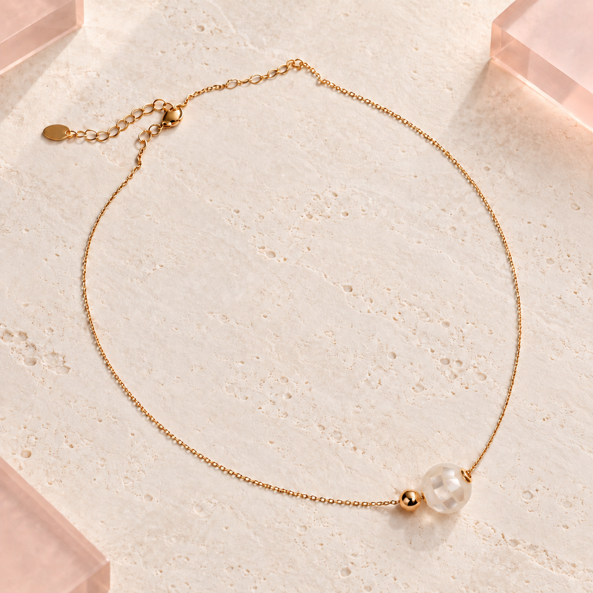 Ivara Faceted Pearl Gold Necklace on Bloomy ivory stone and blush acrylic background