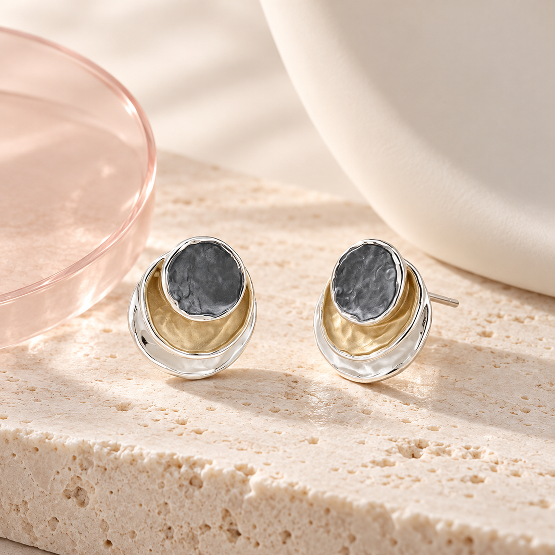 Bloomy Trinity Eclipse Stud Earrings on cream travertine